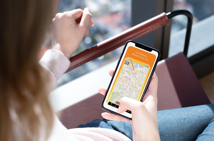 woman holds phone with mobee app on it