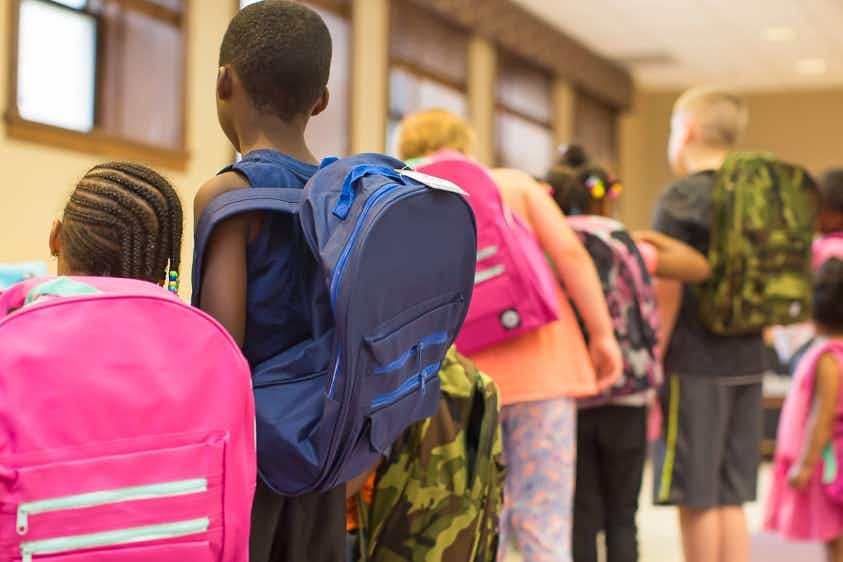 Children standing in a line wearing backpacks