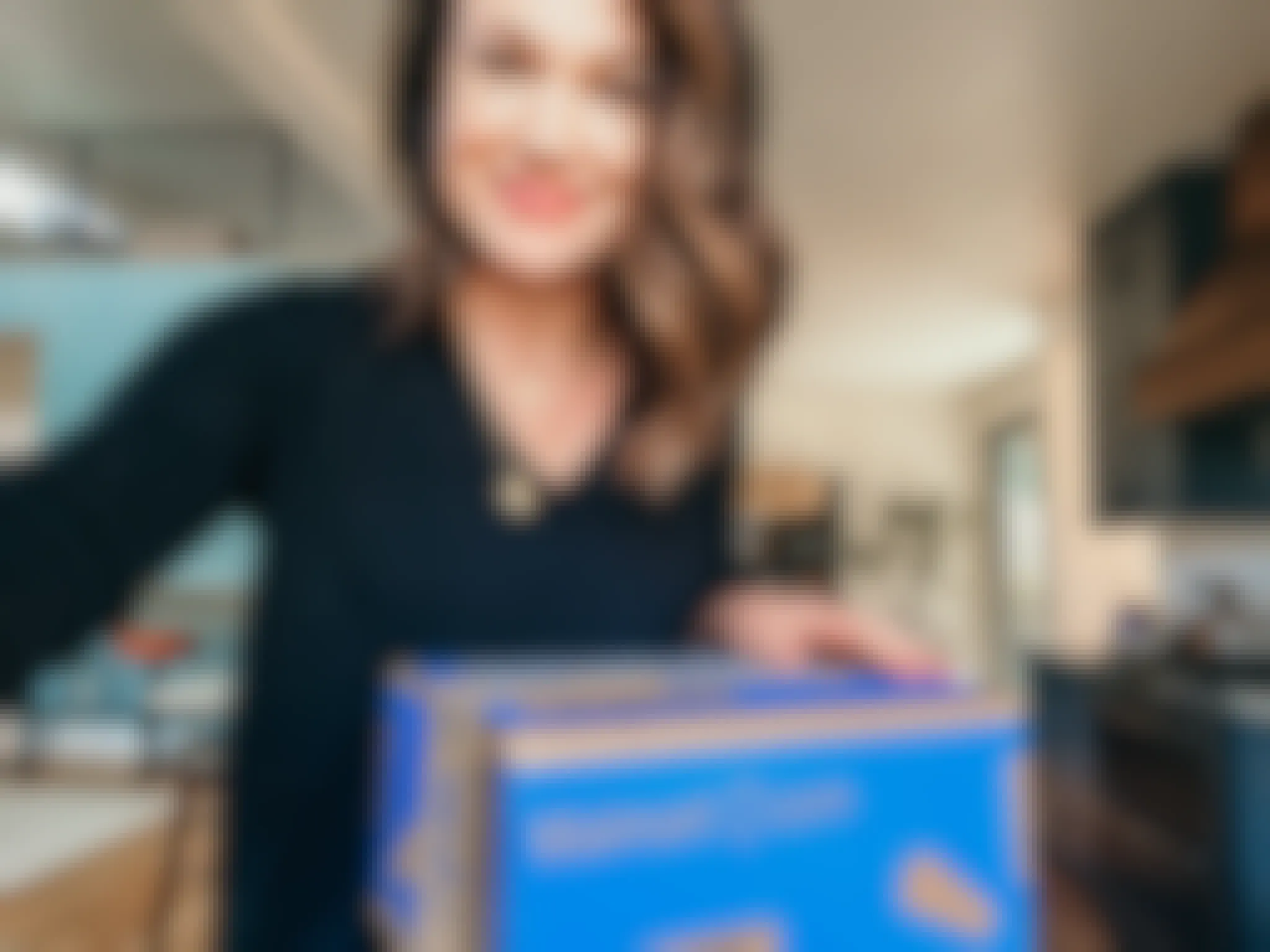 A woman standing in a kitchen with a Walmart+ box.