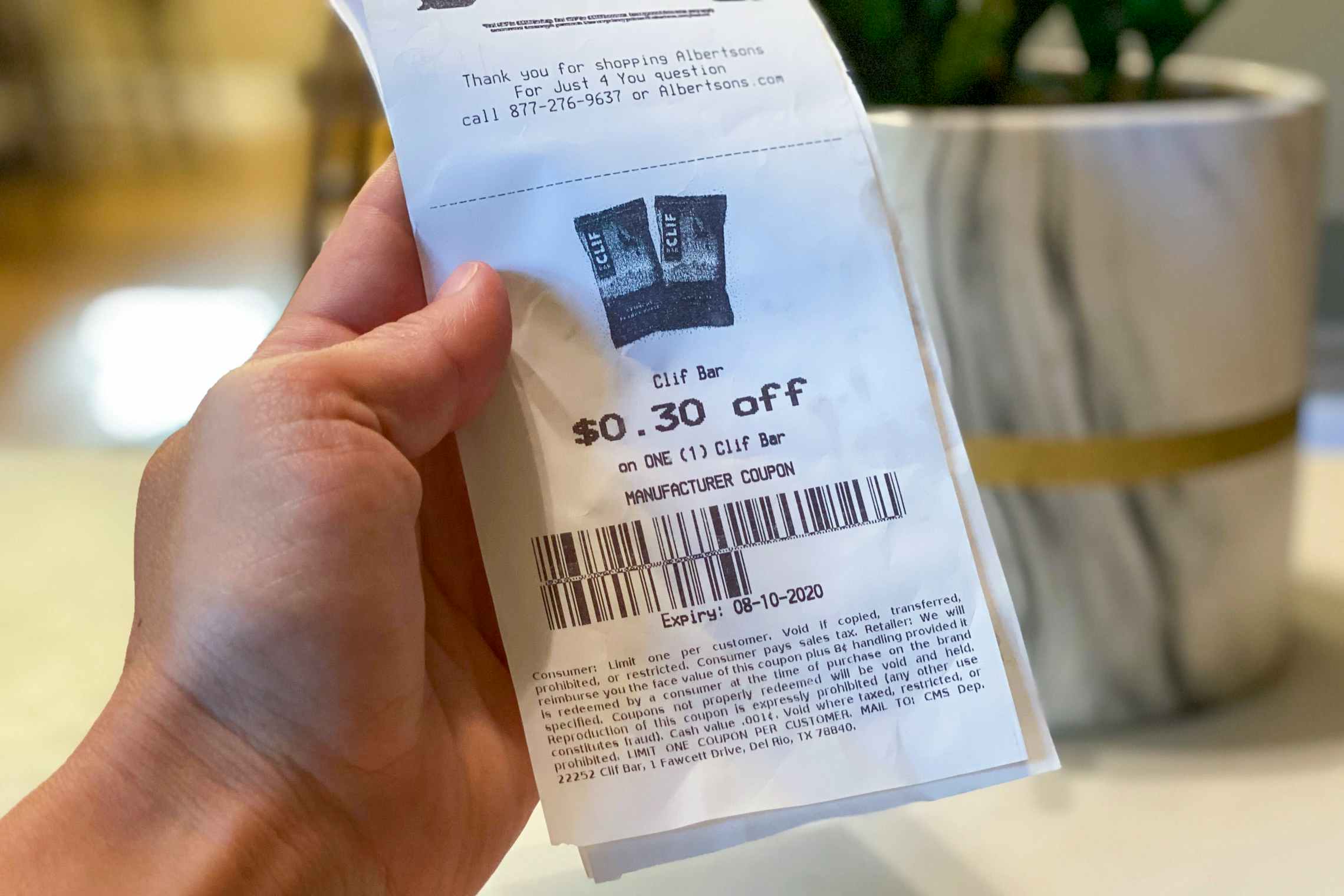 A person holding an Albertsons with a clif bad coupon printed on the bottom.