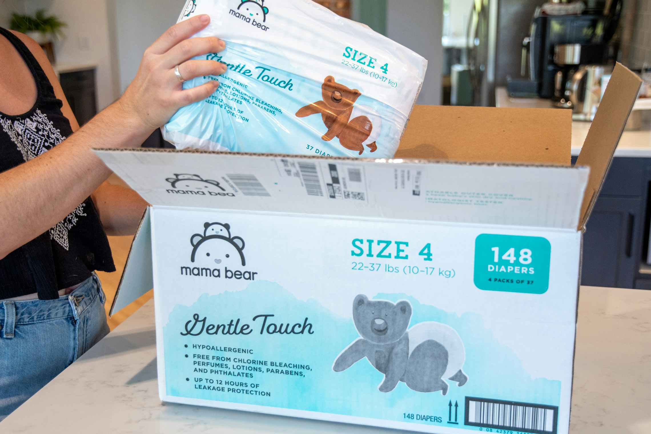 A person pulling a pack of Amazon Mama Bear diapers from a box.