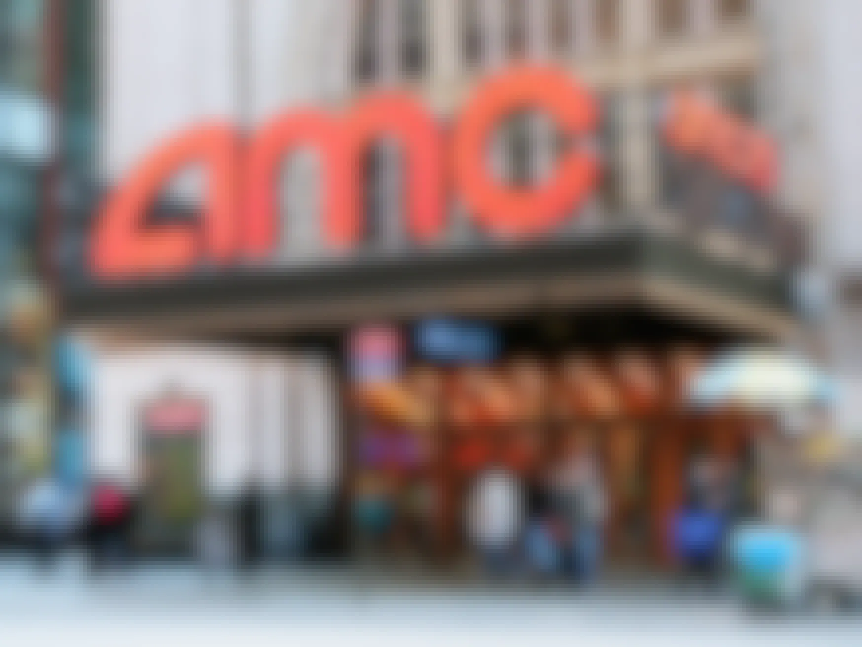 An AMC movie theater entrance with people walking by on the sidewalk.