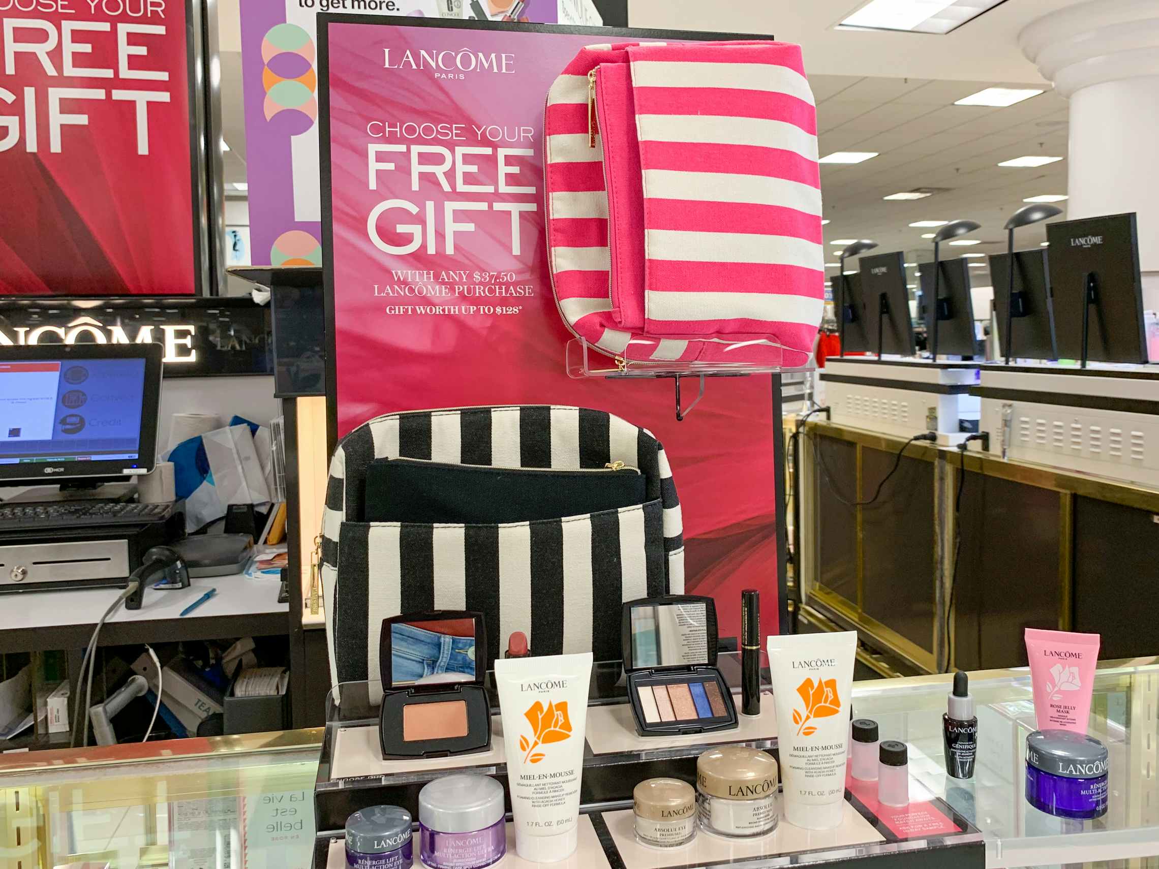 Free gift with purchase sign in the cosmetics section in a Belk store.