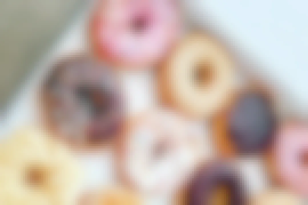 A close-up on a box of different flavored doughnuts sitting open on a table.
