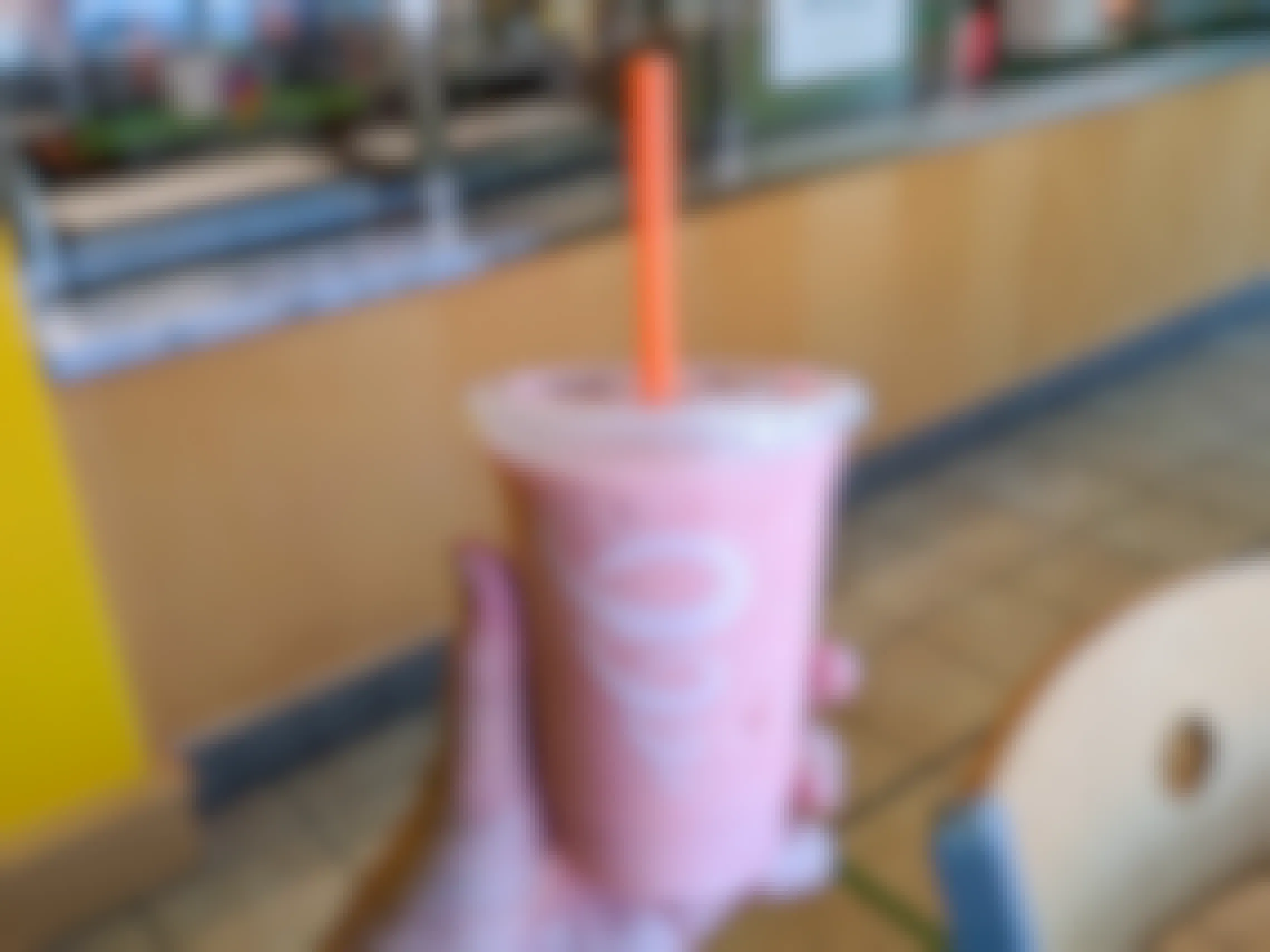 A pink smoothy held in a Jamba Juice.