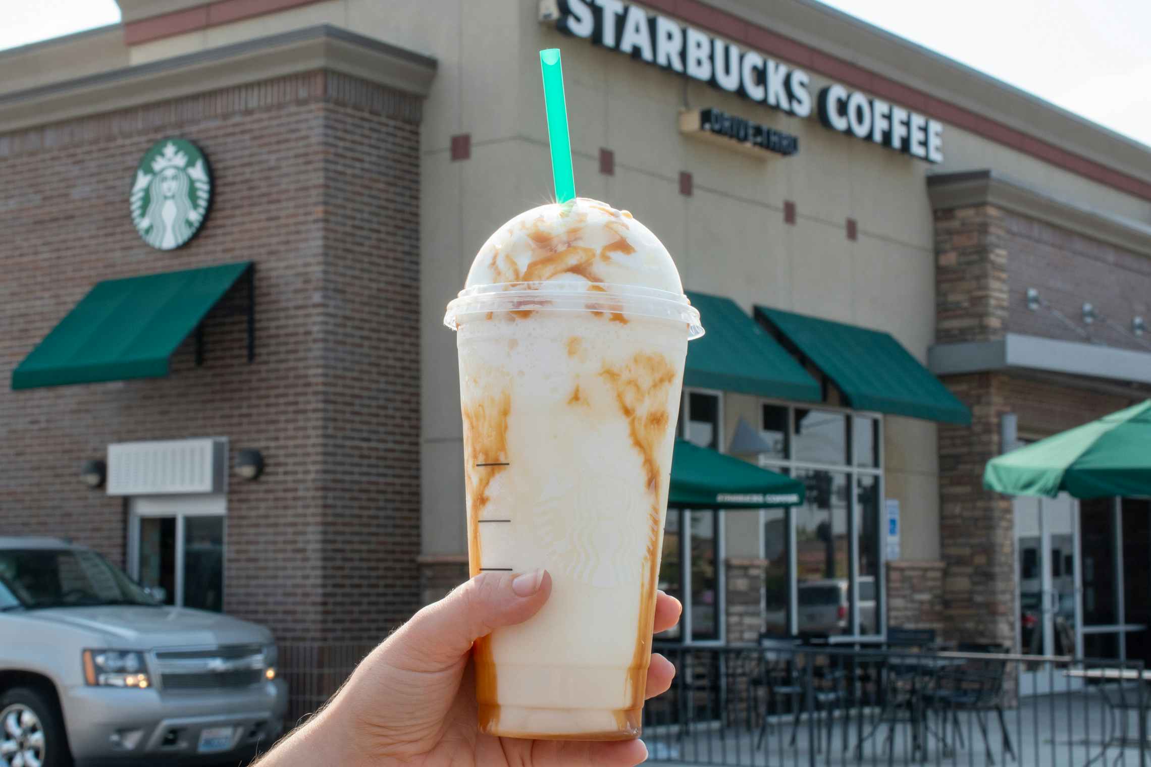 Starbucks frappuccino specialty drink held in front of a Starbucks