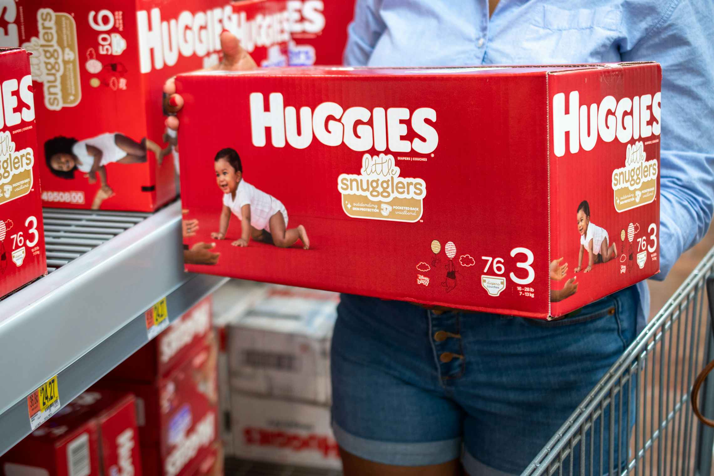 A woman holding a box of Huggies Diapers.