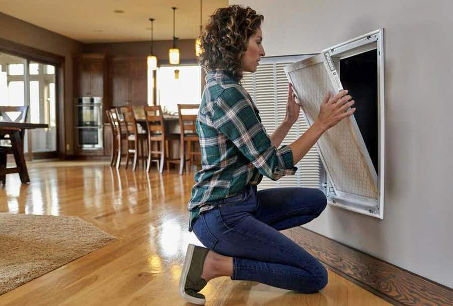 woman changing air filter in her home