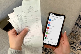 Someone using their iphone with ibotta to save and get cash back with paper receipts