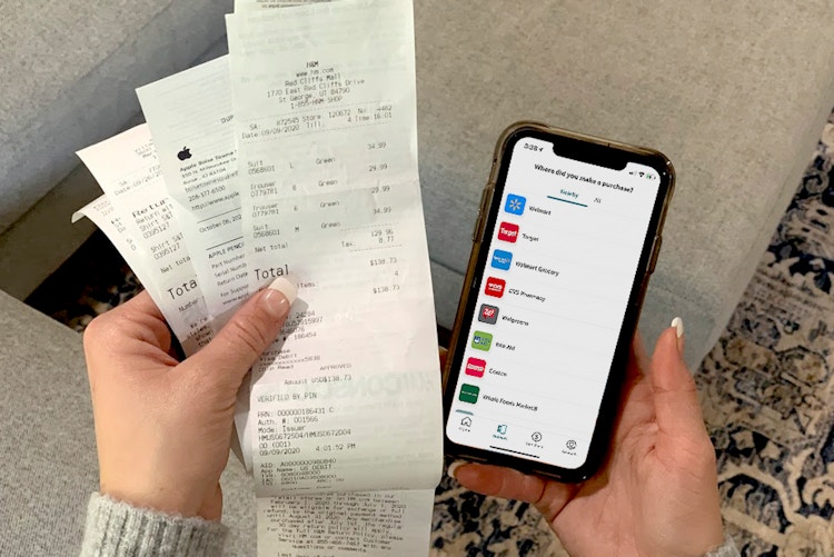 Someone using their iphone with ibotta to save and get cash back with paper receipts