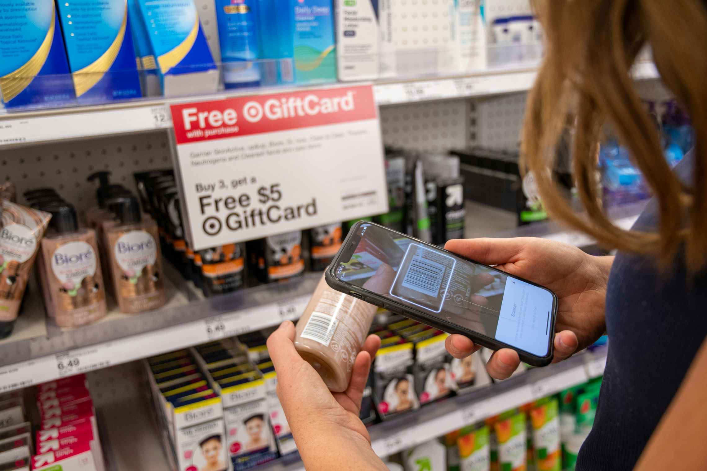 A person using the Target mobile app's barcode scanning feature to scan an item in front of a shelf at Target.