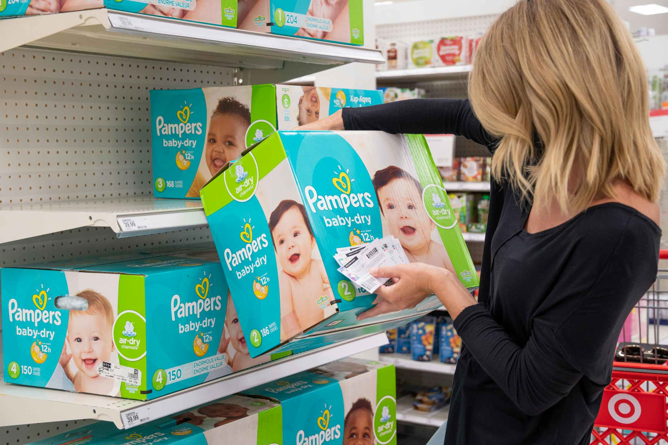 A woman shopping for Pampers diapers with coupons in Target.