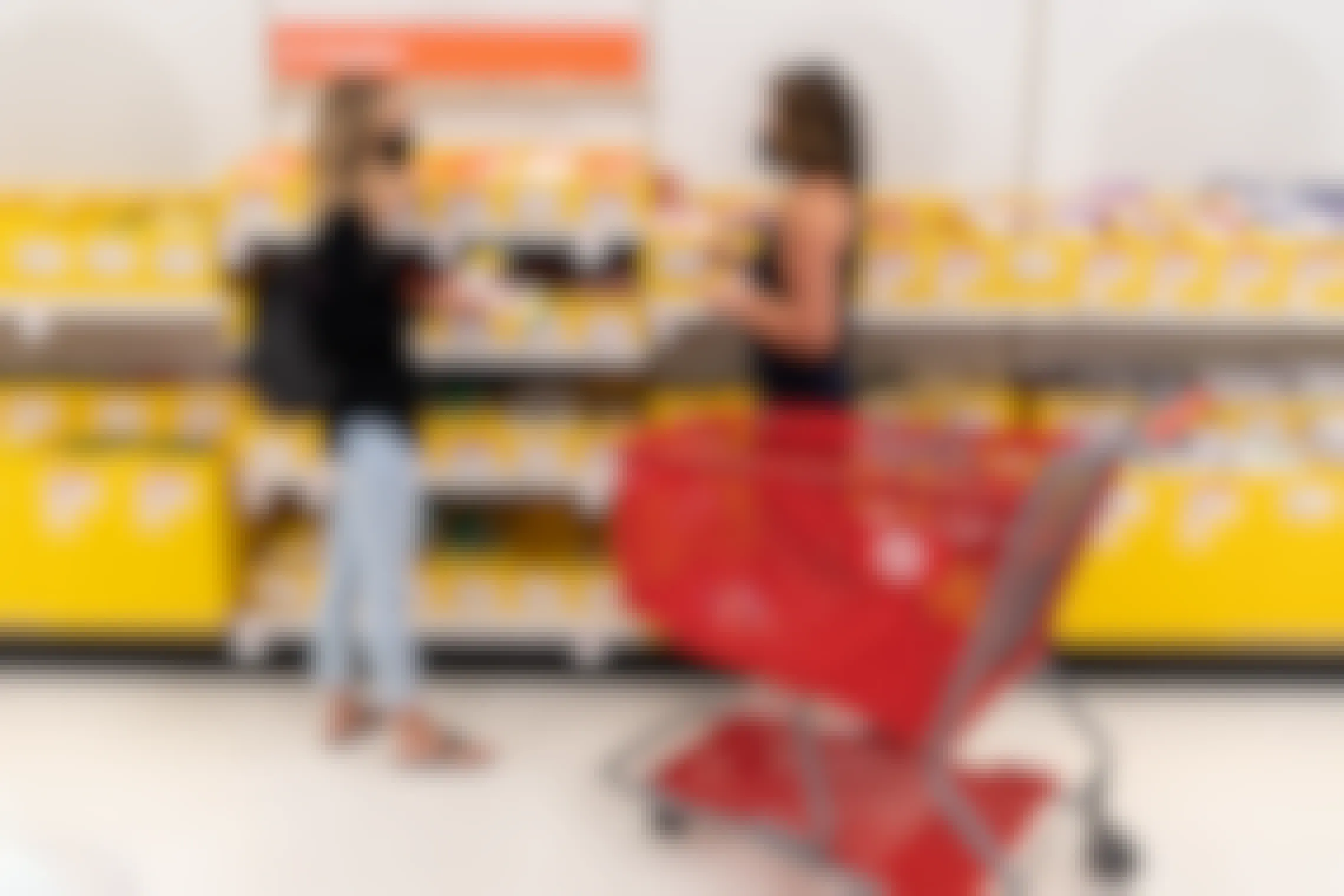 Two women in masks talking to each other next to a Target shopping cart in the school supplies aisle in Target.
