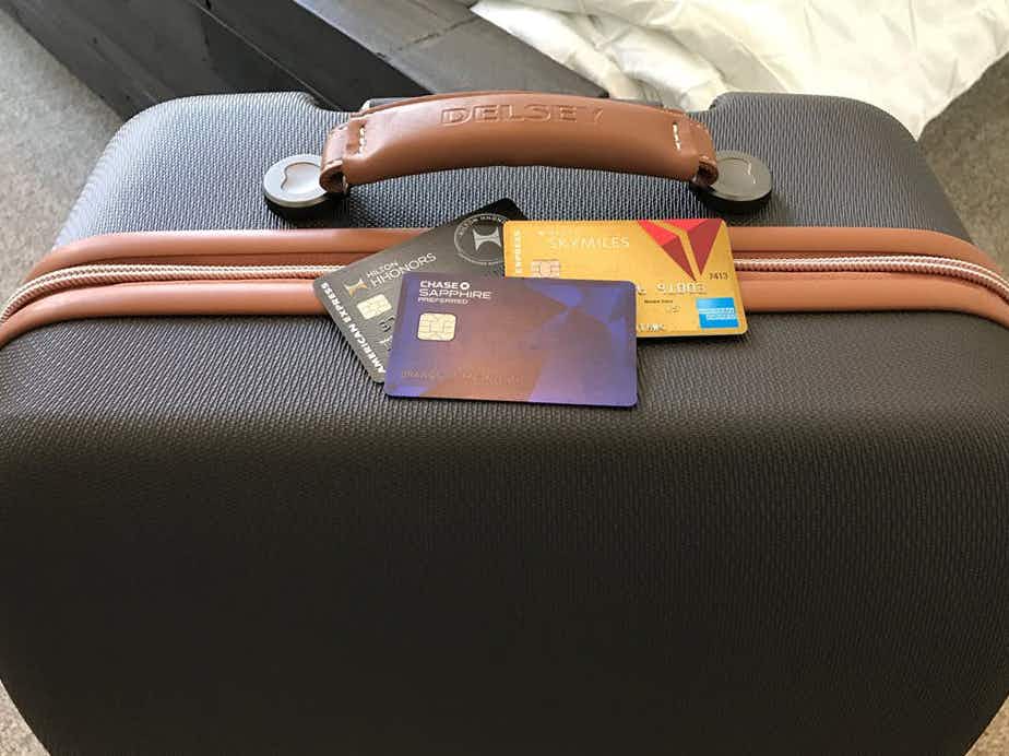 Travel credit cards sitting on top of a suitcase.