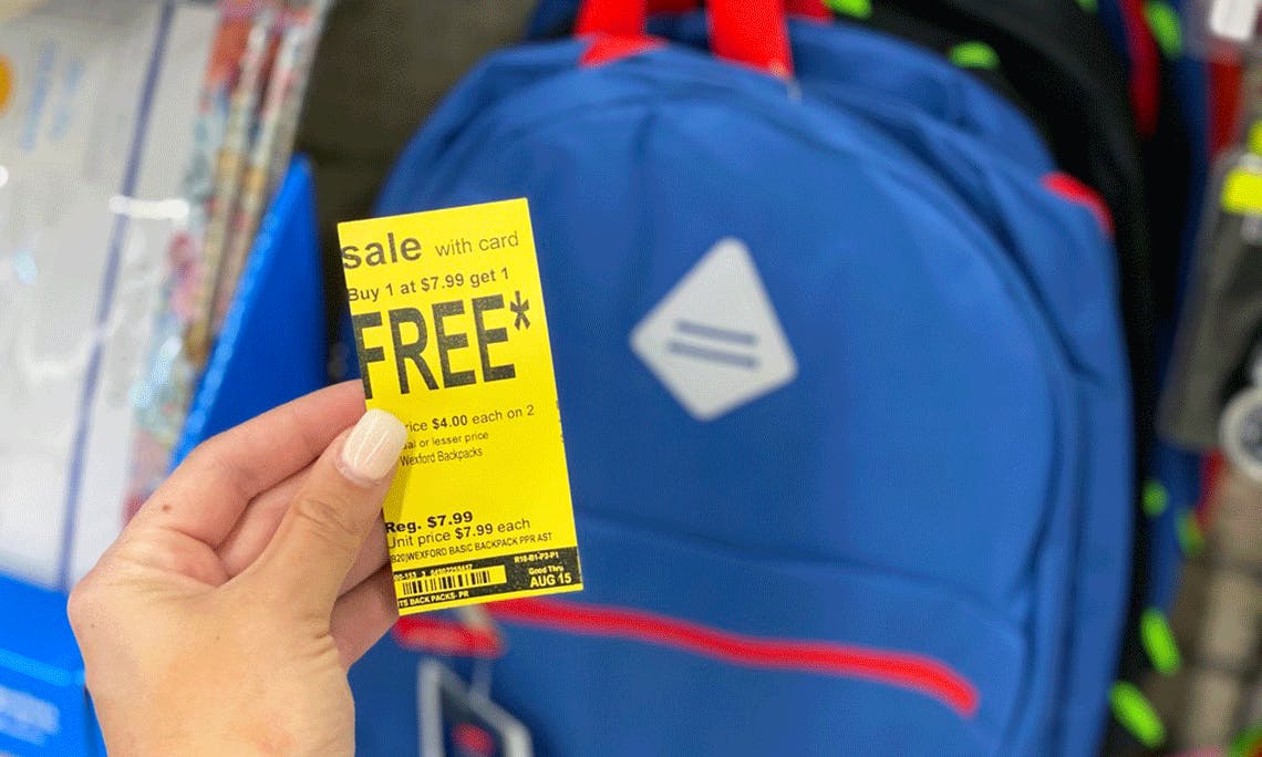 Someone holding a yellow sale sign with a backpack nearby