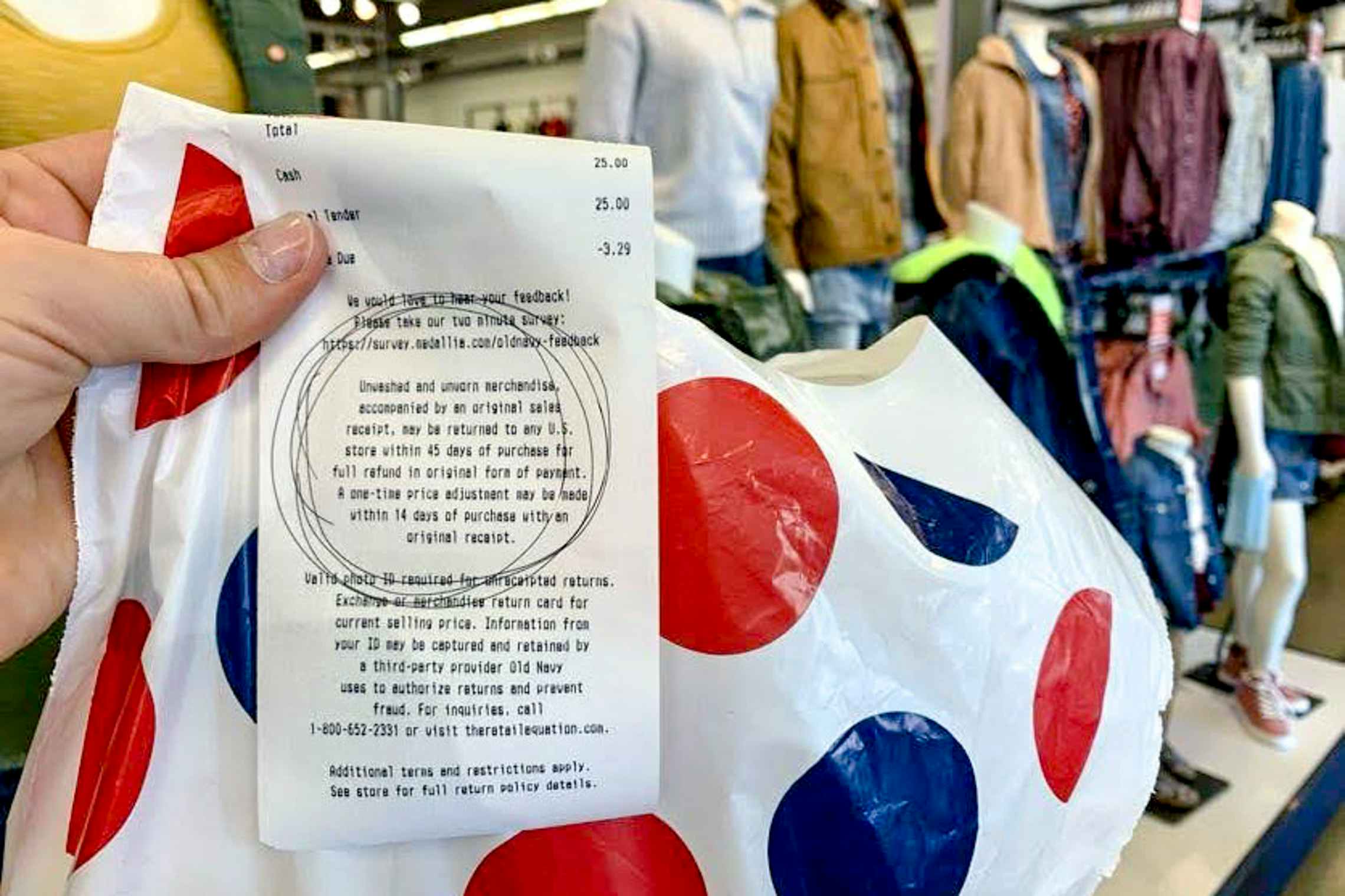 Receipt that has 45 day return policy circled held up with shopping bag inside old navy store