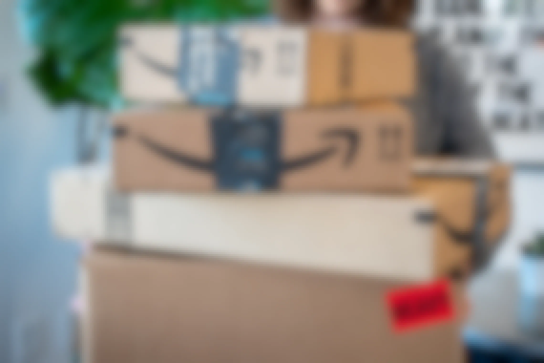 A woman holding a stack of four amazon boxes