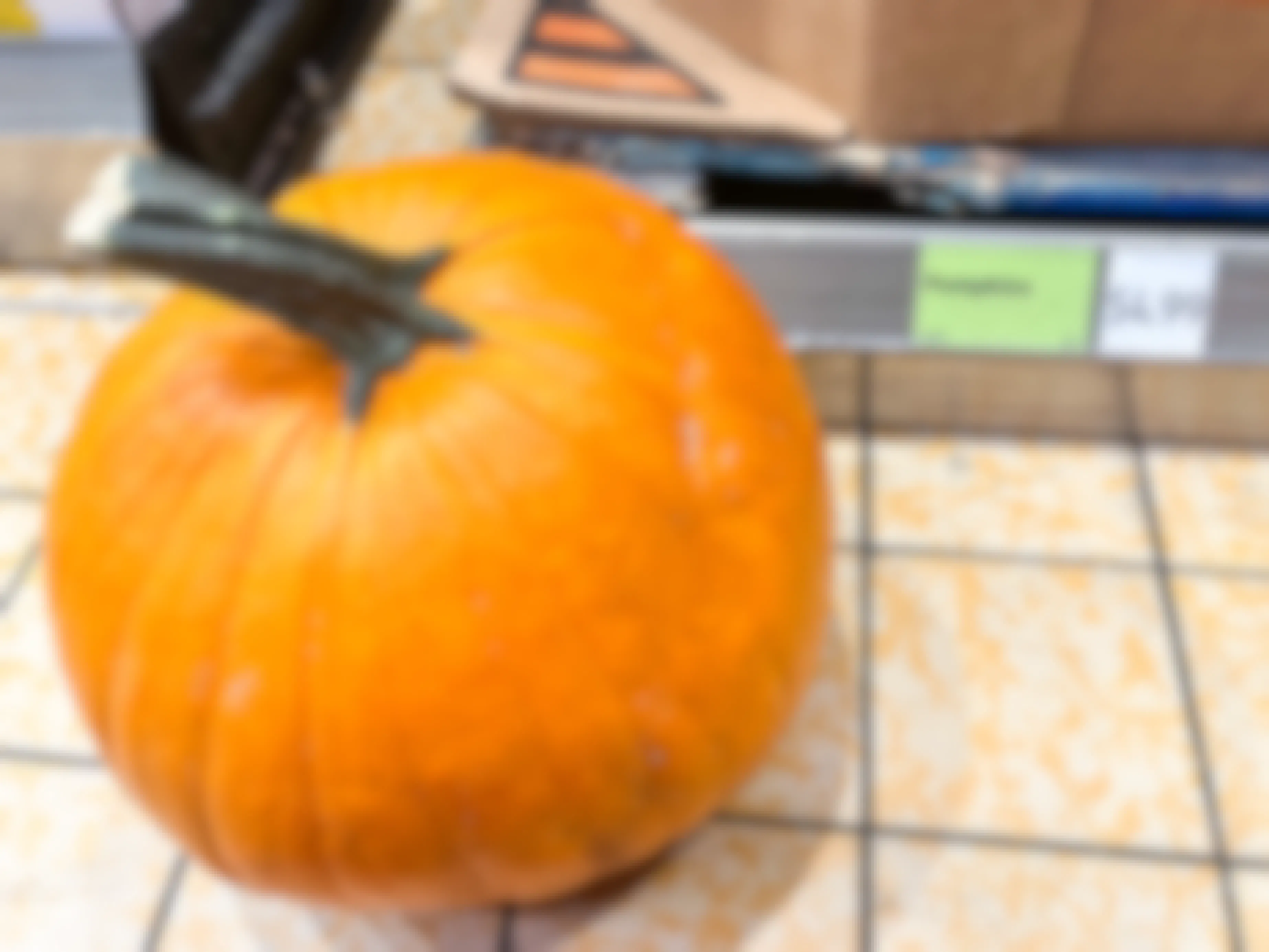 A pumpkin from Aldi on the floor next to the price tag which reads, "$4.99