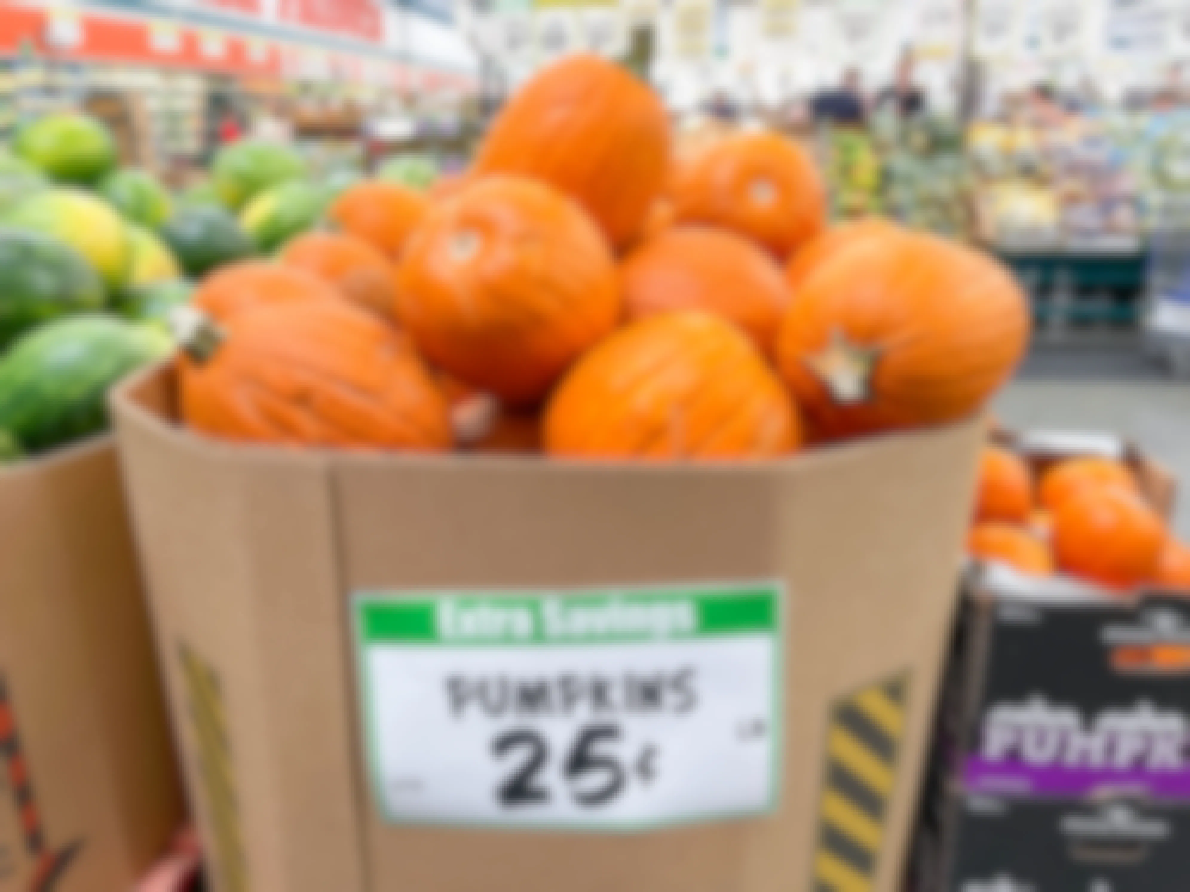 A large box filled with pumpkins in the produce section at WinCo Foods with a price sign for 25 cents a pound..