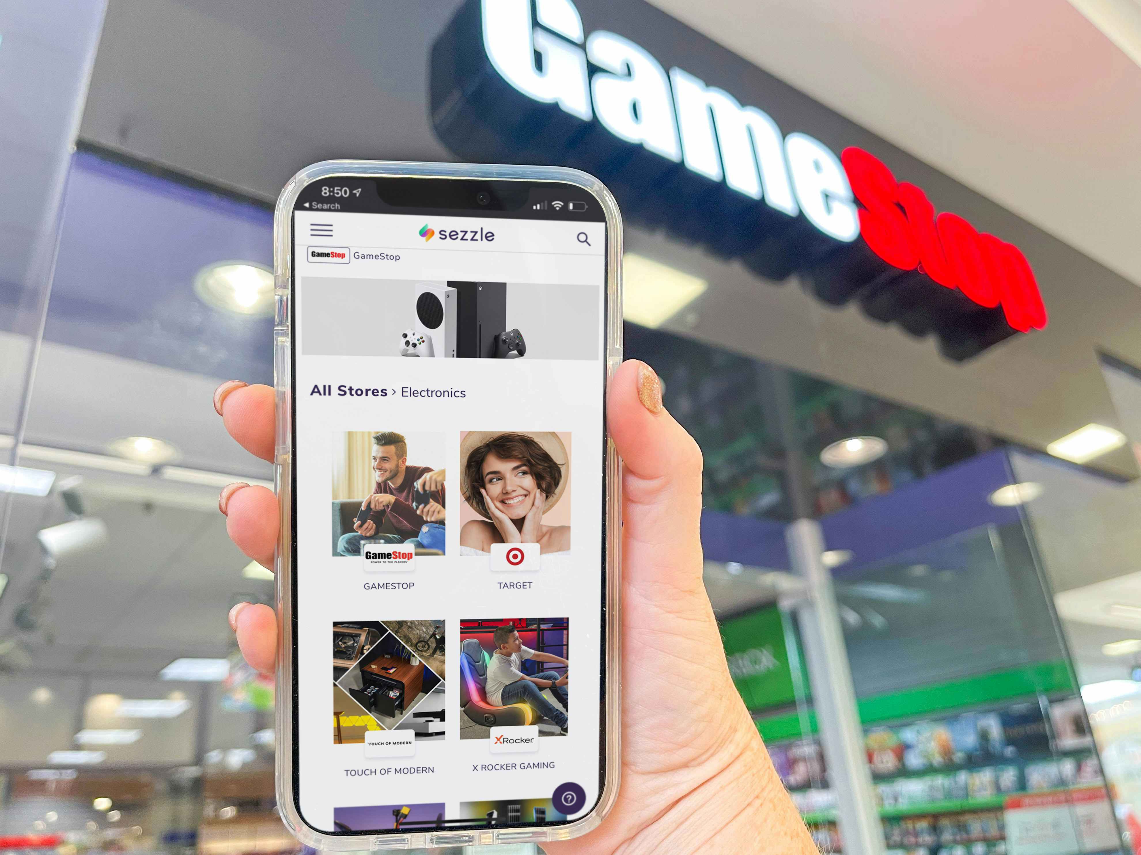 cellphone being held with sezzle buy now pay later app in front of game stop