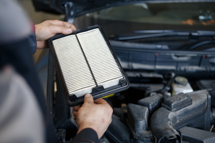 Hand of a man changes and check air filter of car in the engine