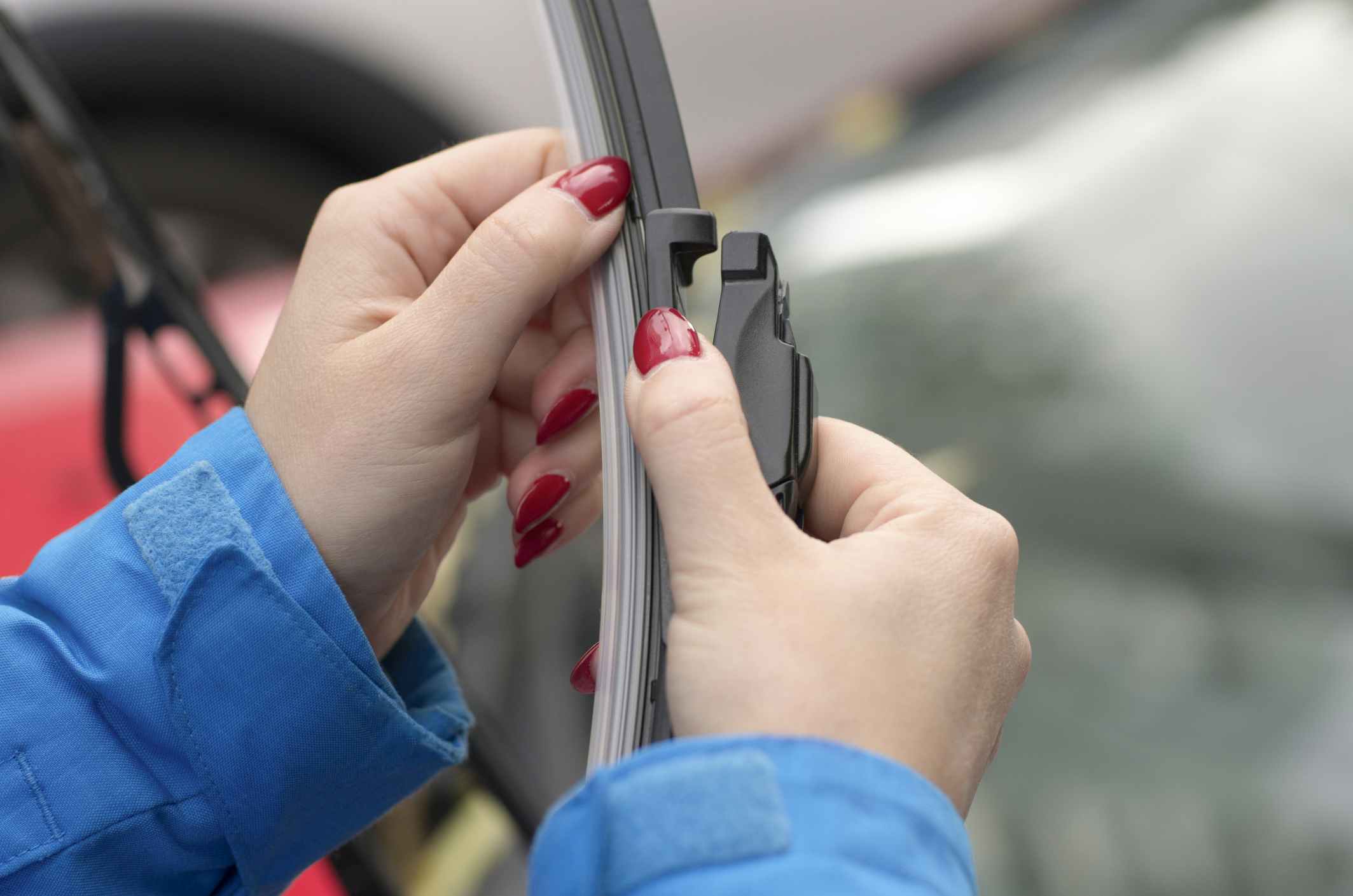 Young girl with red nails is preparing to put a new car windshield wiper brush to replace the old wiper blade