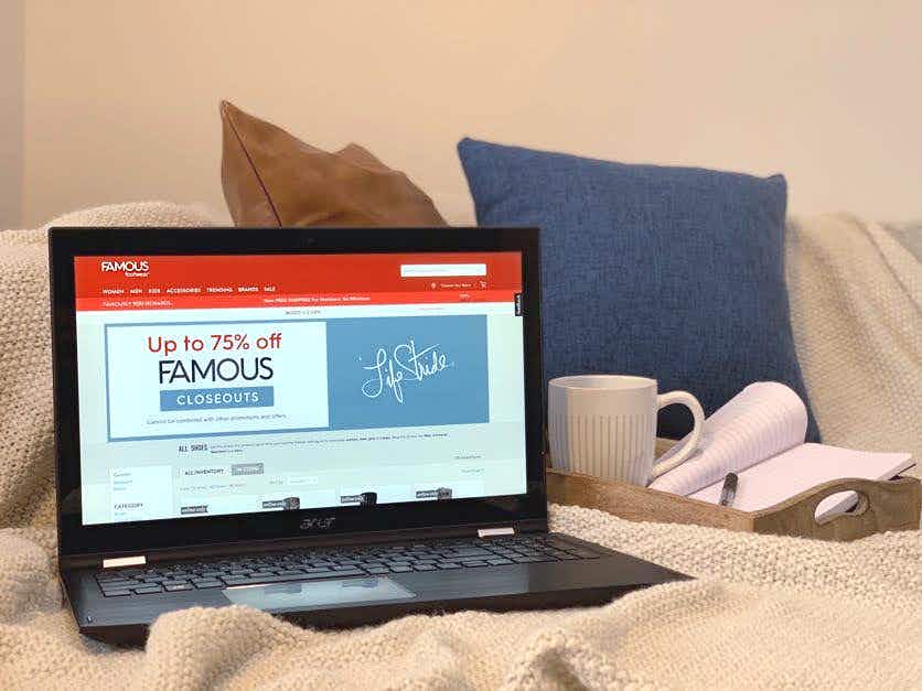 Computer on a couch and the screen reads "up to 75% off famous closeouts