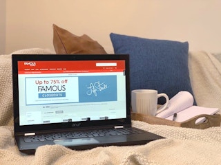 Computer on a couch and the screen reads "up to 75% off famous closeouts