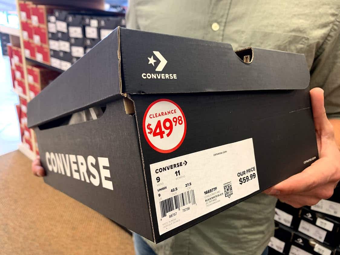 Man holding a converse shoe box that has a clearance sticker for $49.98