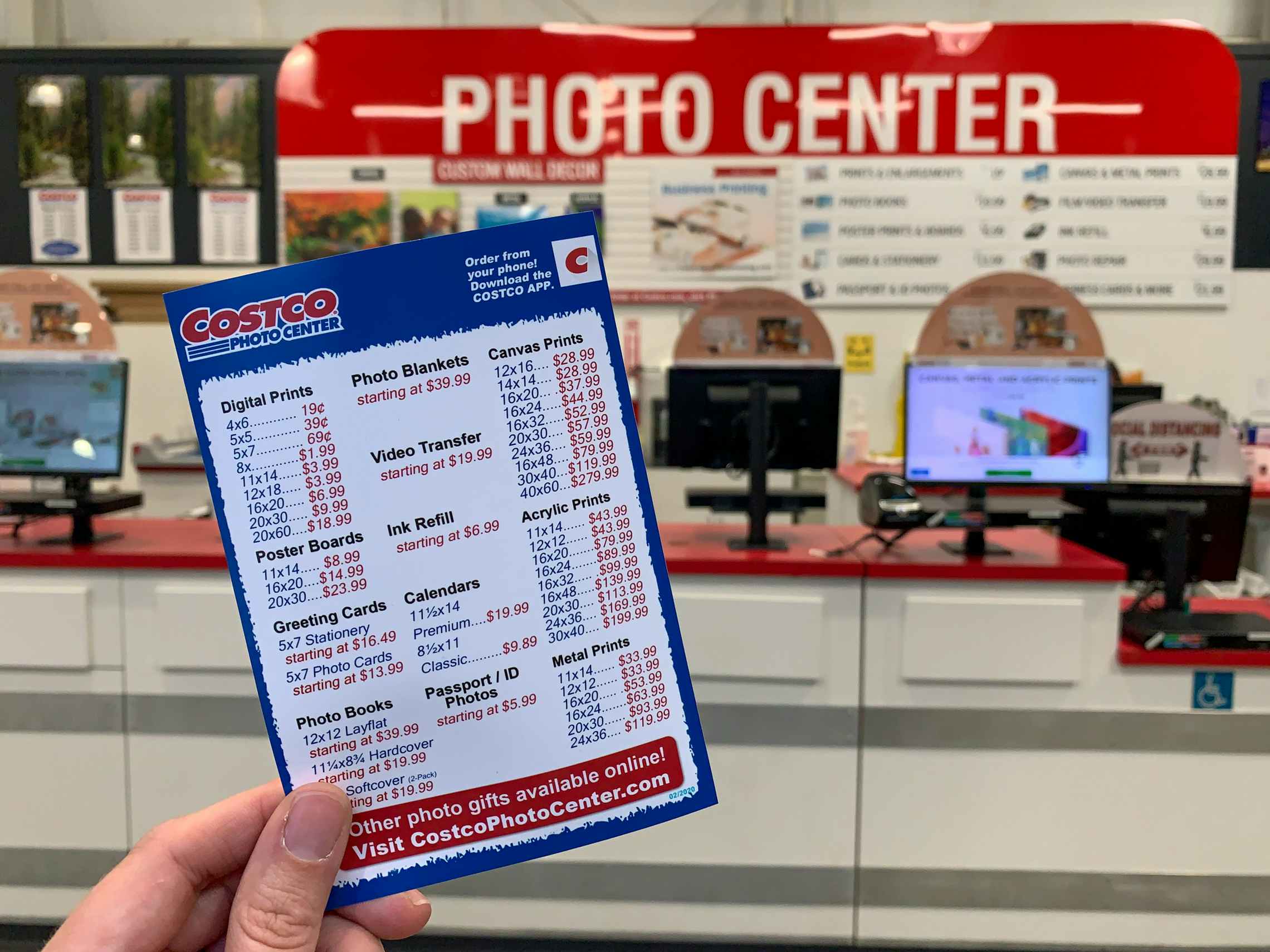 A person holding a costco photo printing price list in front of the photo center