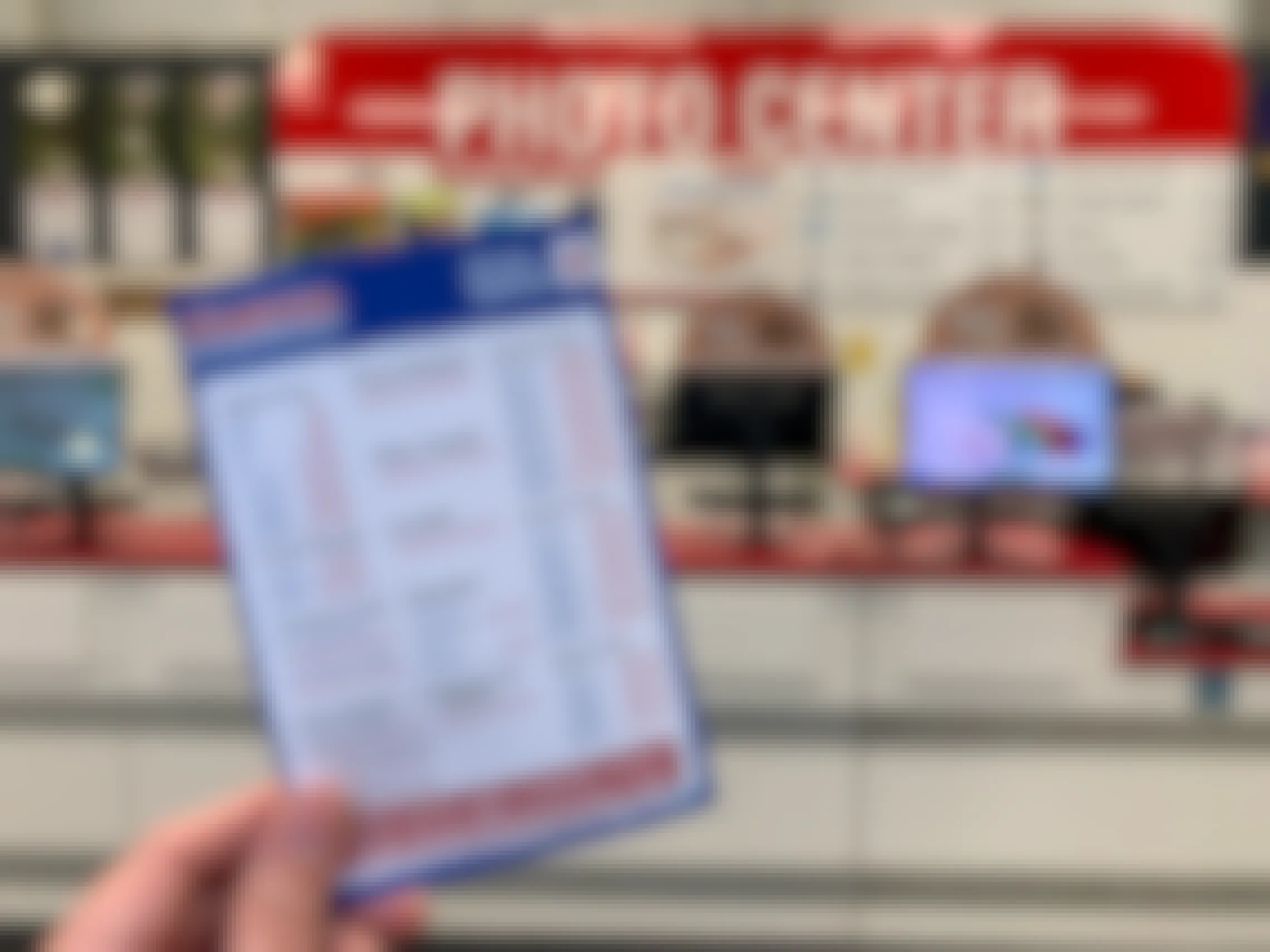 A person holding a costco photo printing price list in front of the photo center