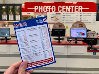 A person holding a costco photo printing price list in front of the photo center