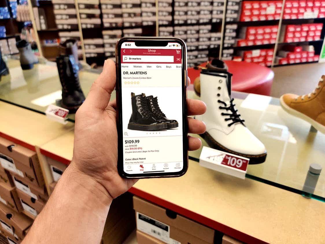 A phone held up in front of Dr. Martins shoes showing "bogo 1st pair only