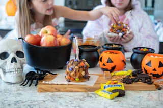 Caramel apple, apples, and candy in a small plastic cauldrons and pumpkins.