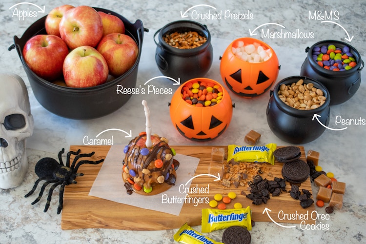 Caramel apple, apples, and candy in a small plastic cauldrons and pumpkins.