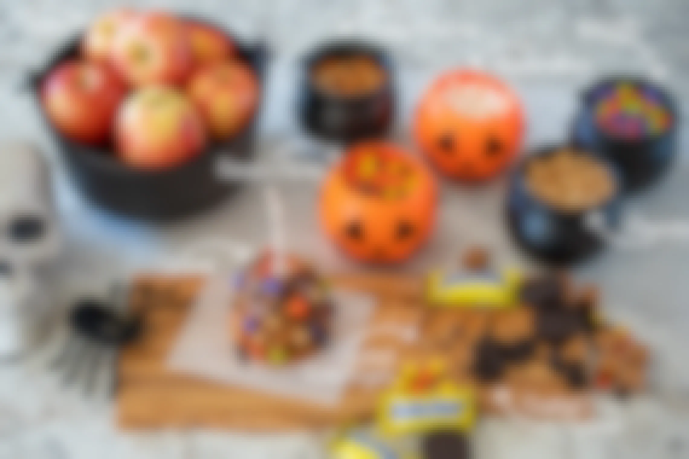 Caramel apple, apples, and candy in a small plastic cauldrons and pumpkins.