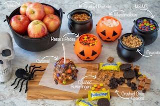 Caramel apple, apples, and candy in a small plastic cauldrons and pumpkins.