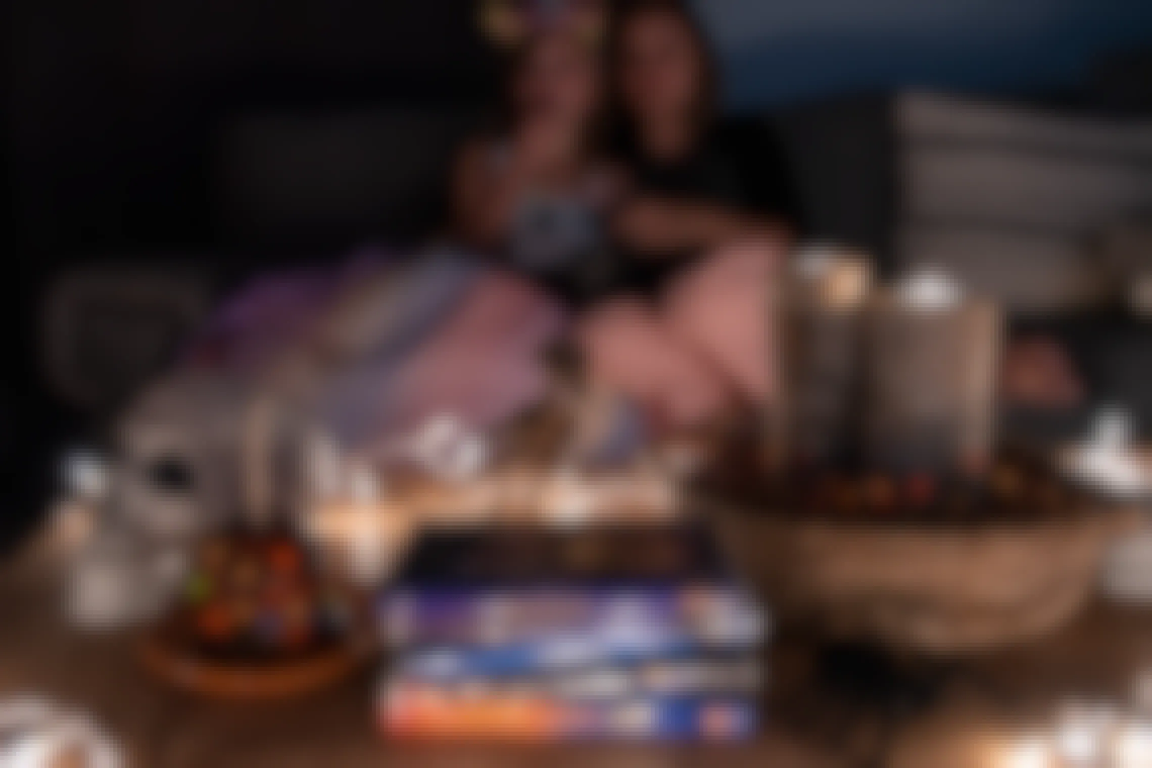 A woman and child eating popcorn watching a movie, with a table filled with treats, candles, and other halloween kids movies.