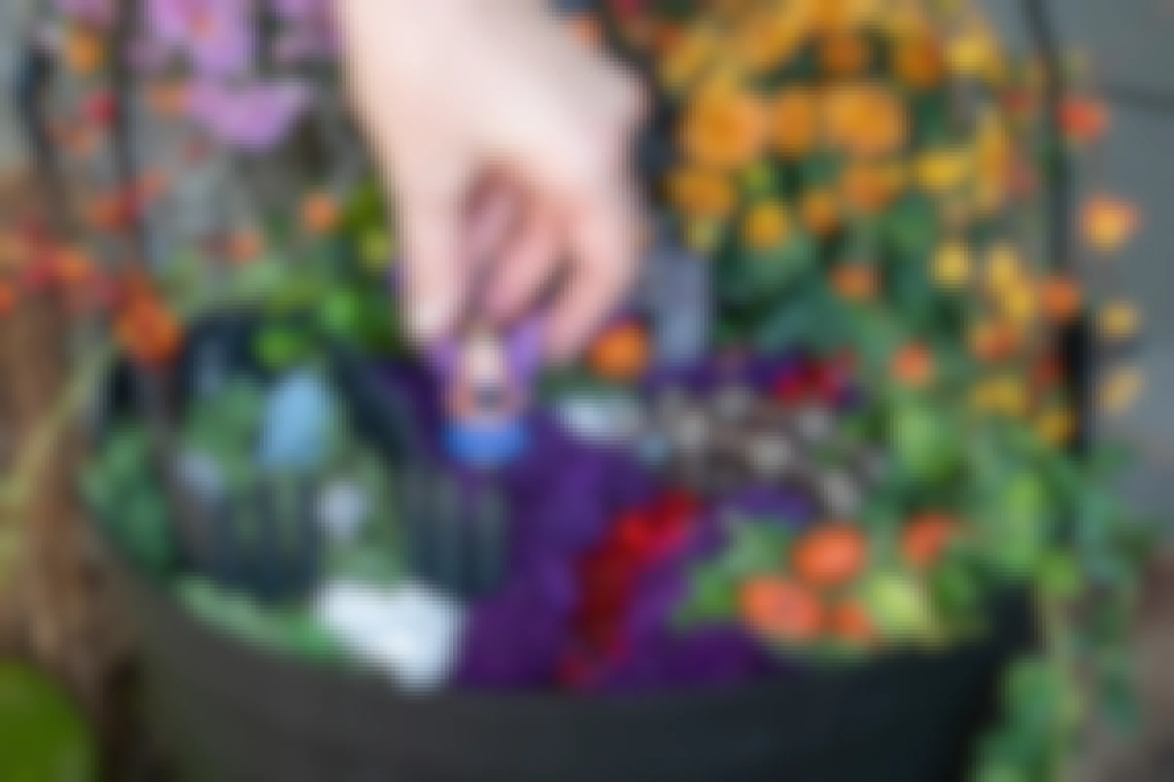 A woman putting a small fairy witch into a Halloween themed fairy garden