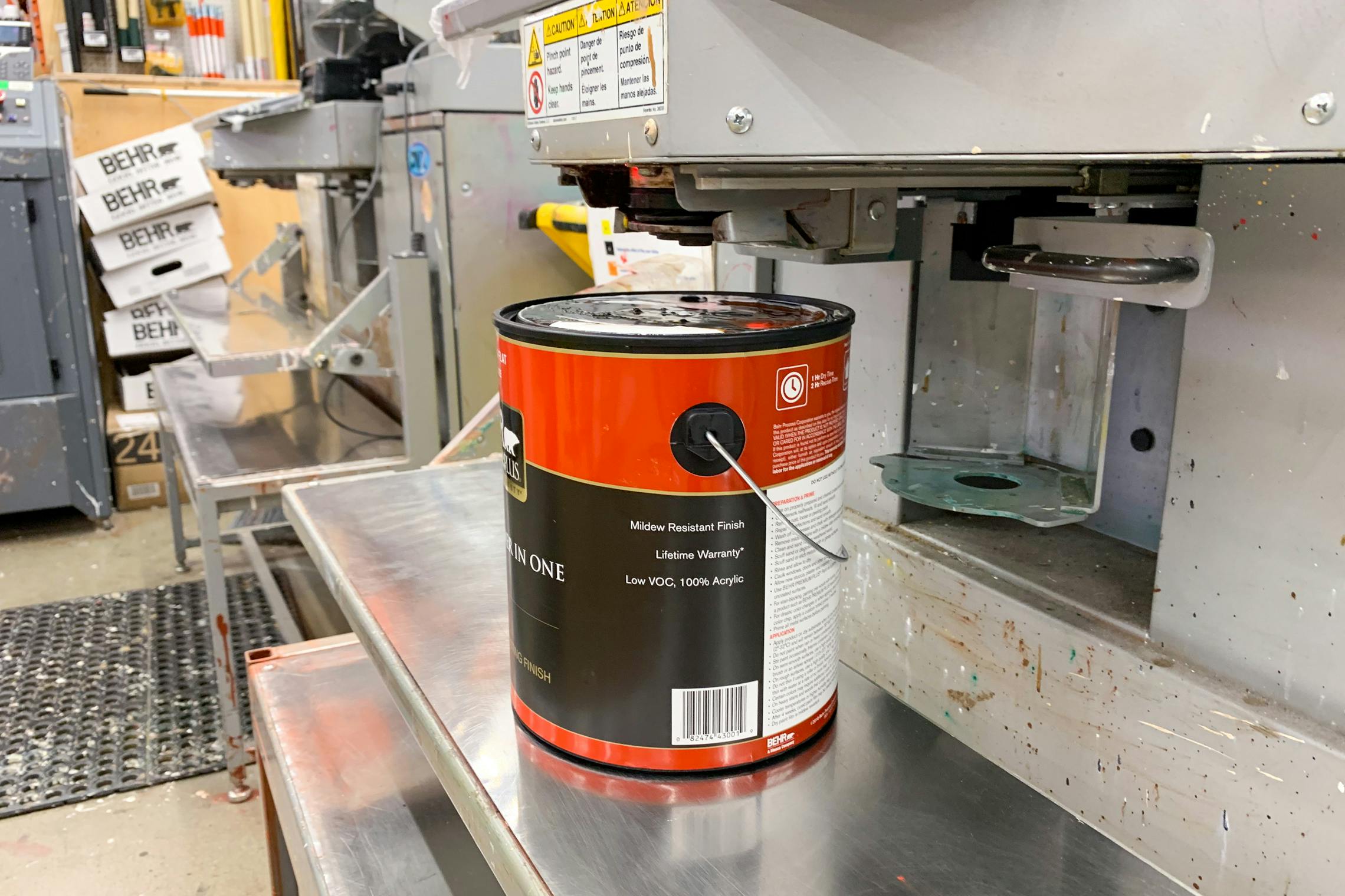 An open can of paint sitting below the machine used for tinting paint.