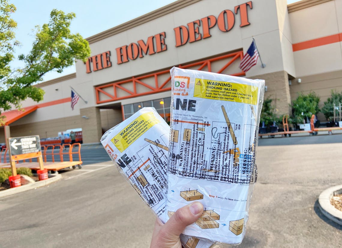 A person holding two Home Depot kids workshop kits.