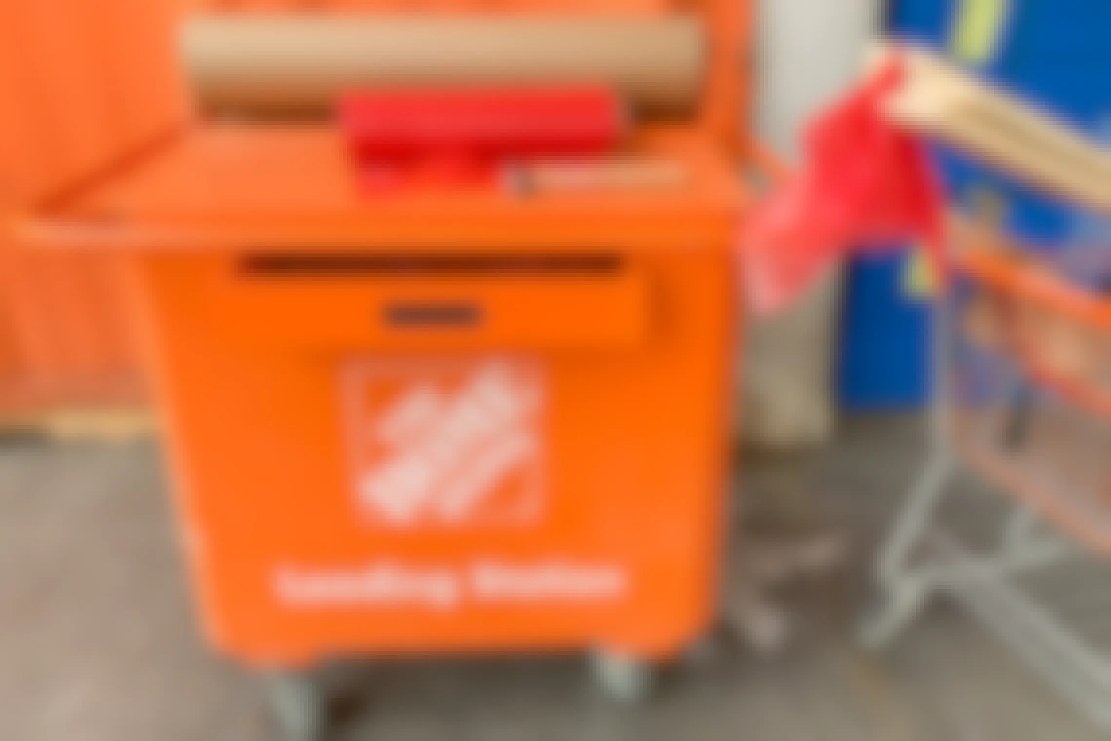 The home depot loading station cart with a hammer, red plastic flags and brown paper next to a cart with lumber in it.