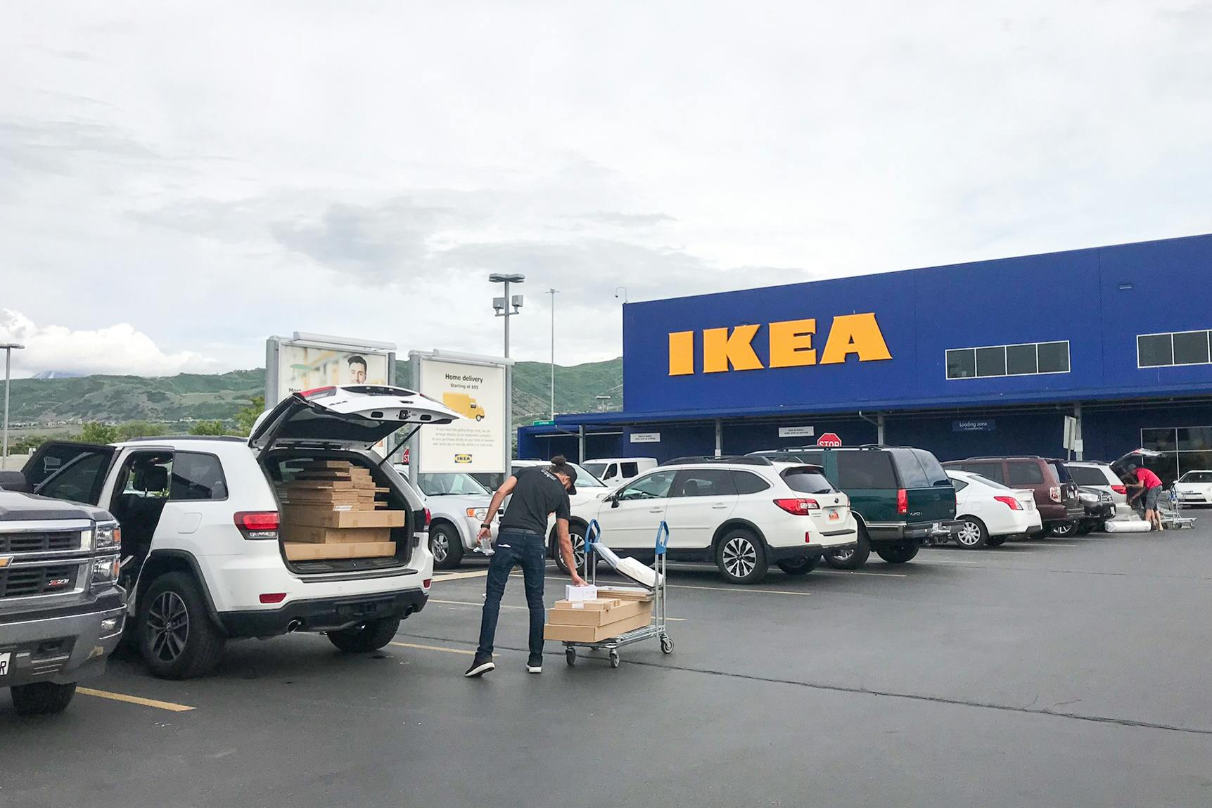 Man loading Ikea package into his vehicle outside Ikea.