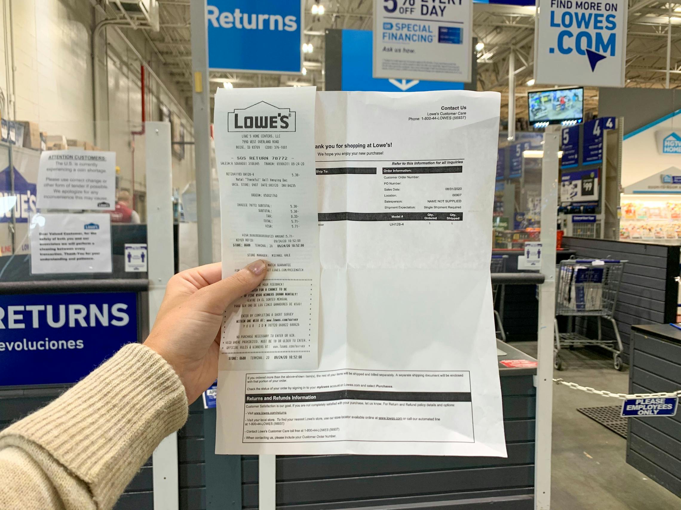 A person's hand holding up their Lowe's black friday return receipt at the Lowe's return counter.