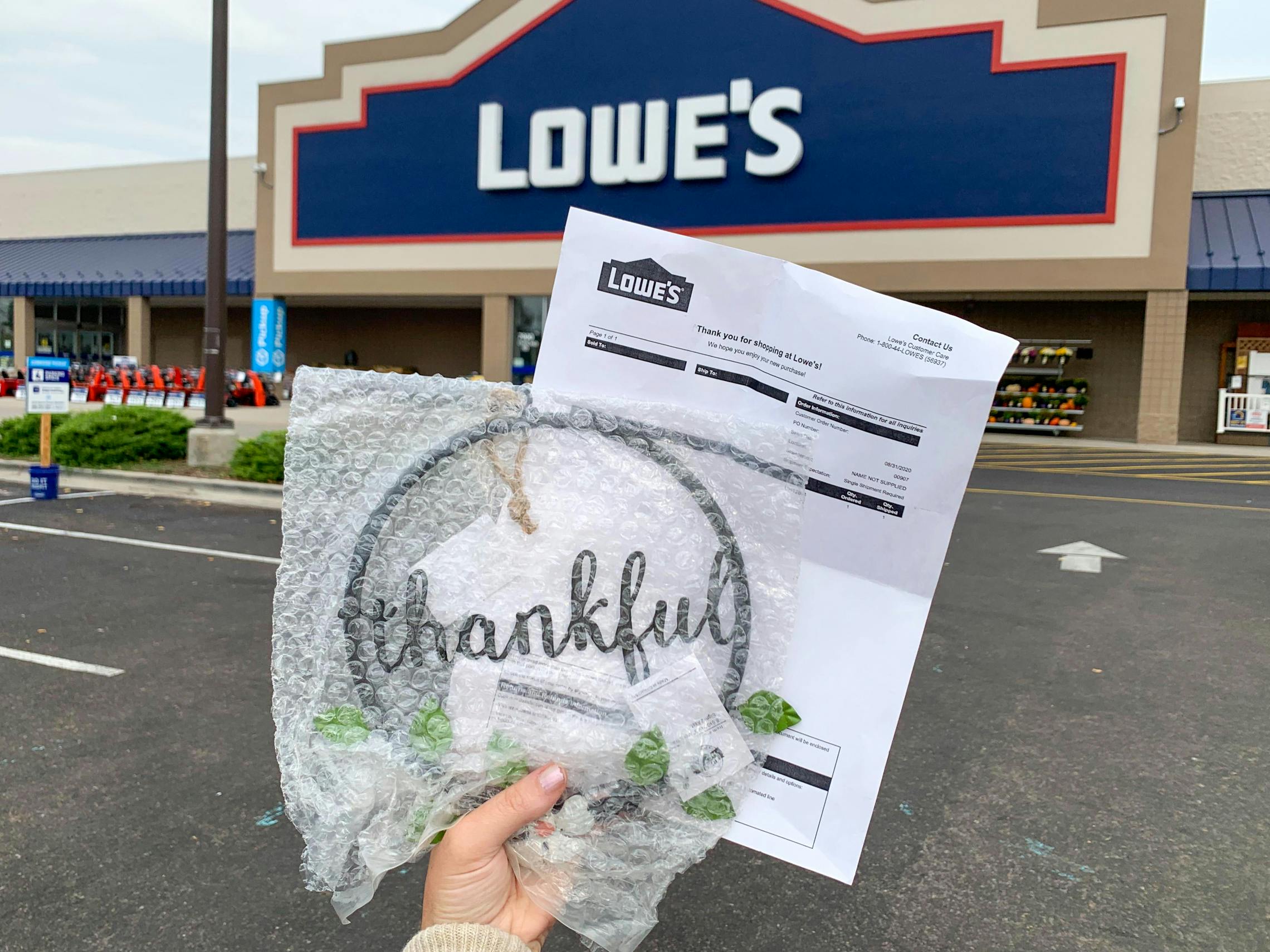 A Lowes return receipt and a thankful sign held in front of Lowes