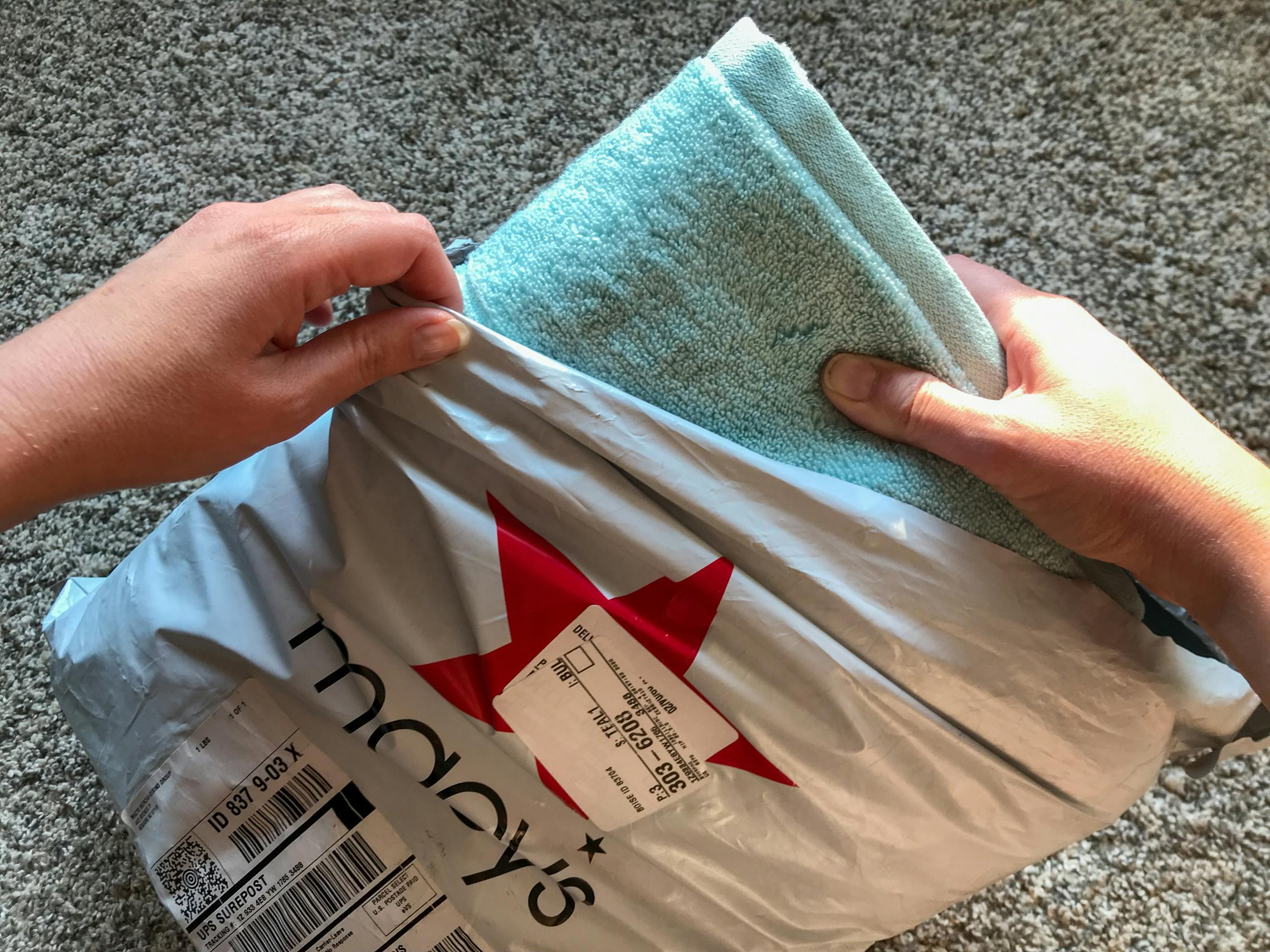 A woman pulling out a towel from a macys online order bag.