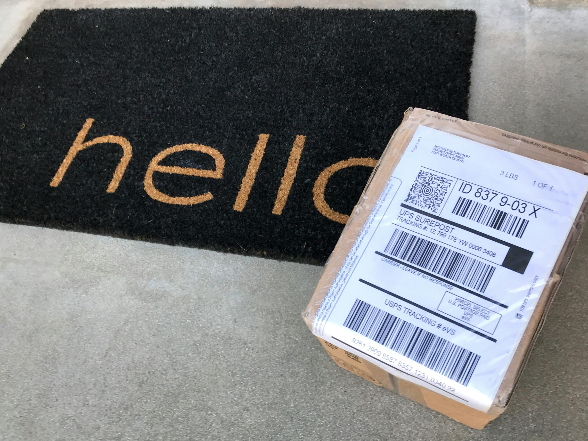 a box with a shipping label is sitting on a front porch on a welcome mat