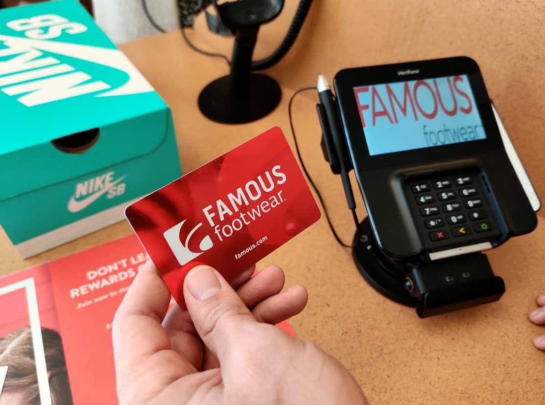 Famous Footwear gift card held up in front of register at check out