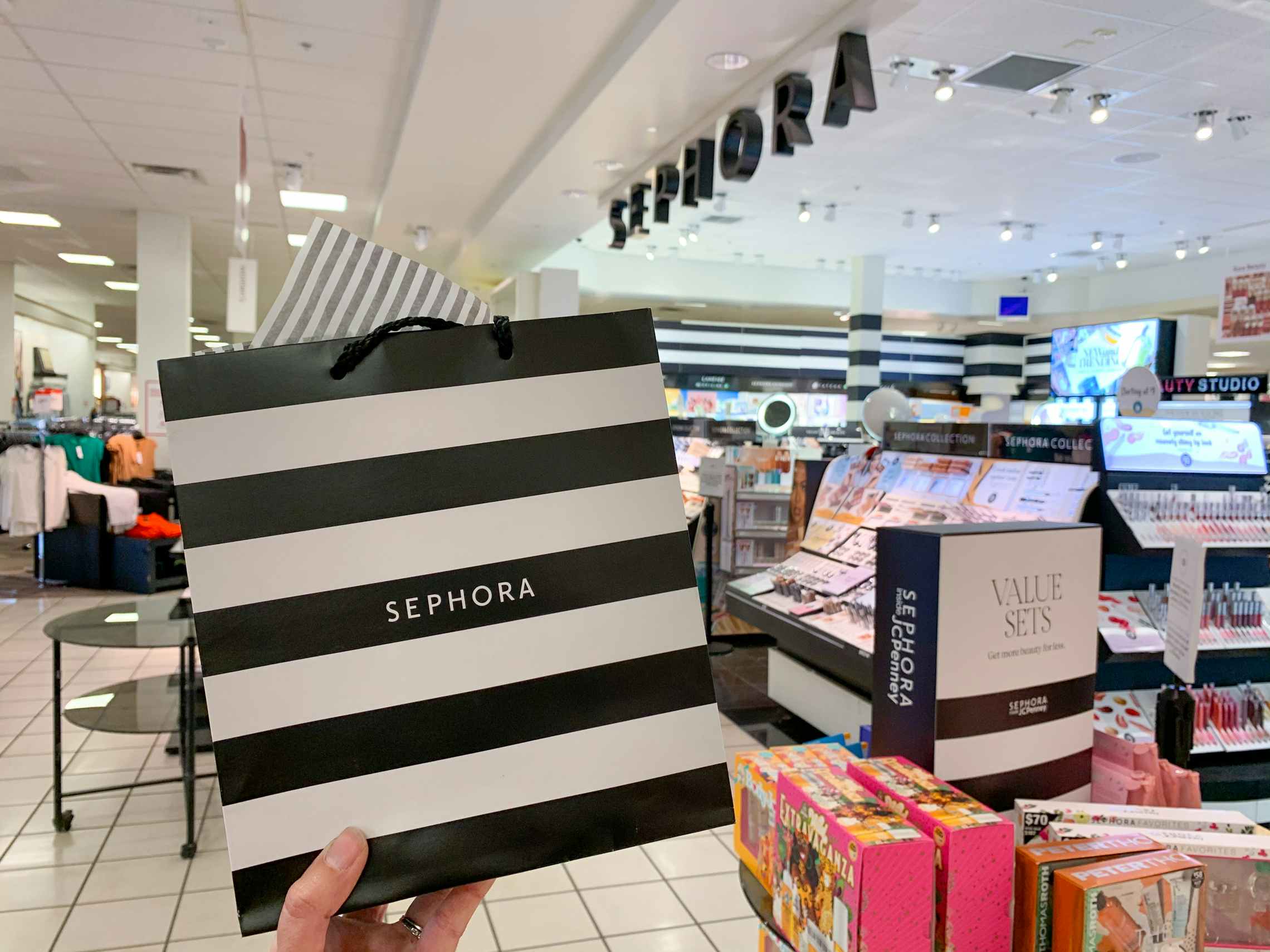 A person holding up a Sephora bag in front of Sephora inside JCPenney