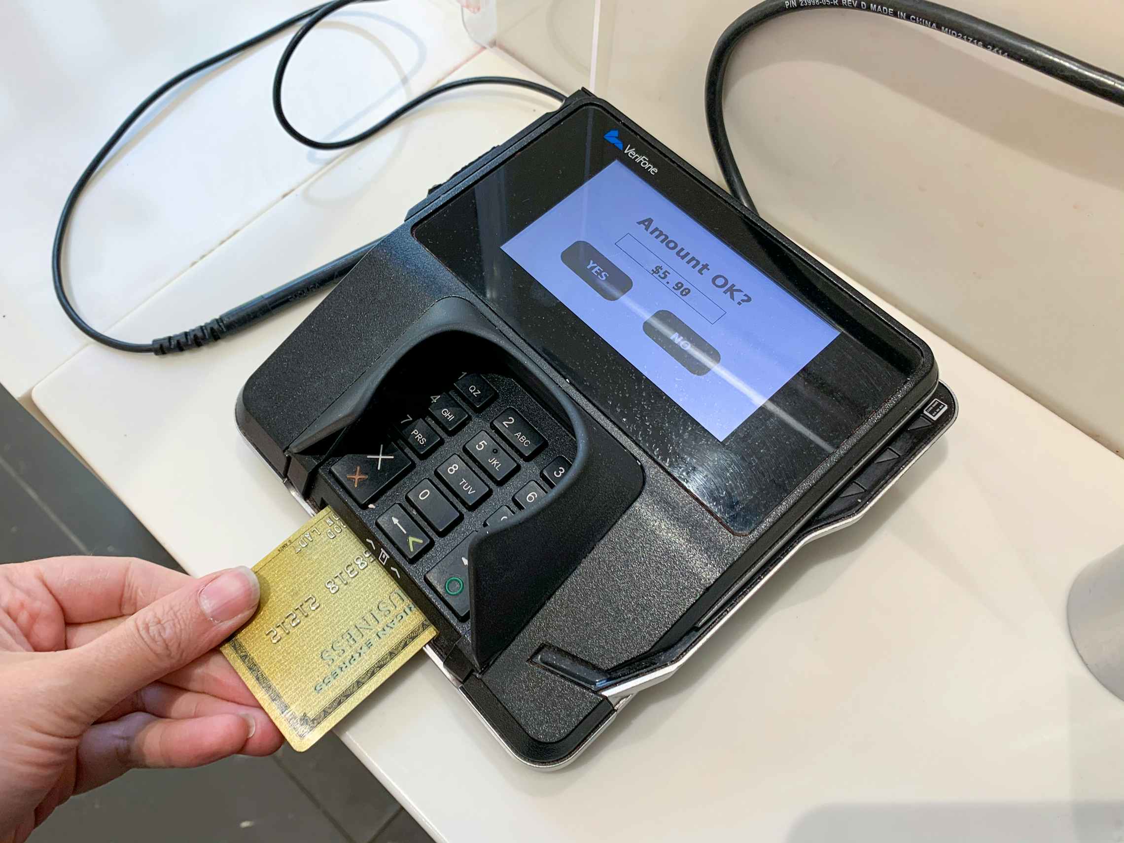 A person putting a credit card into a credit card reader at checkout